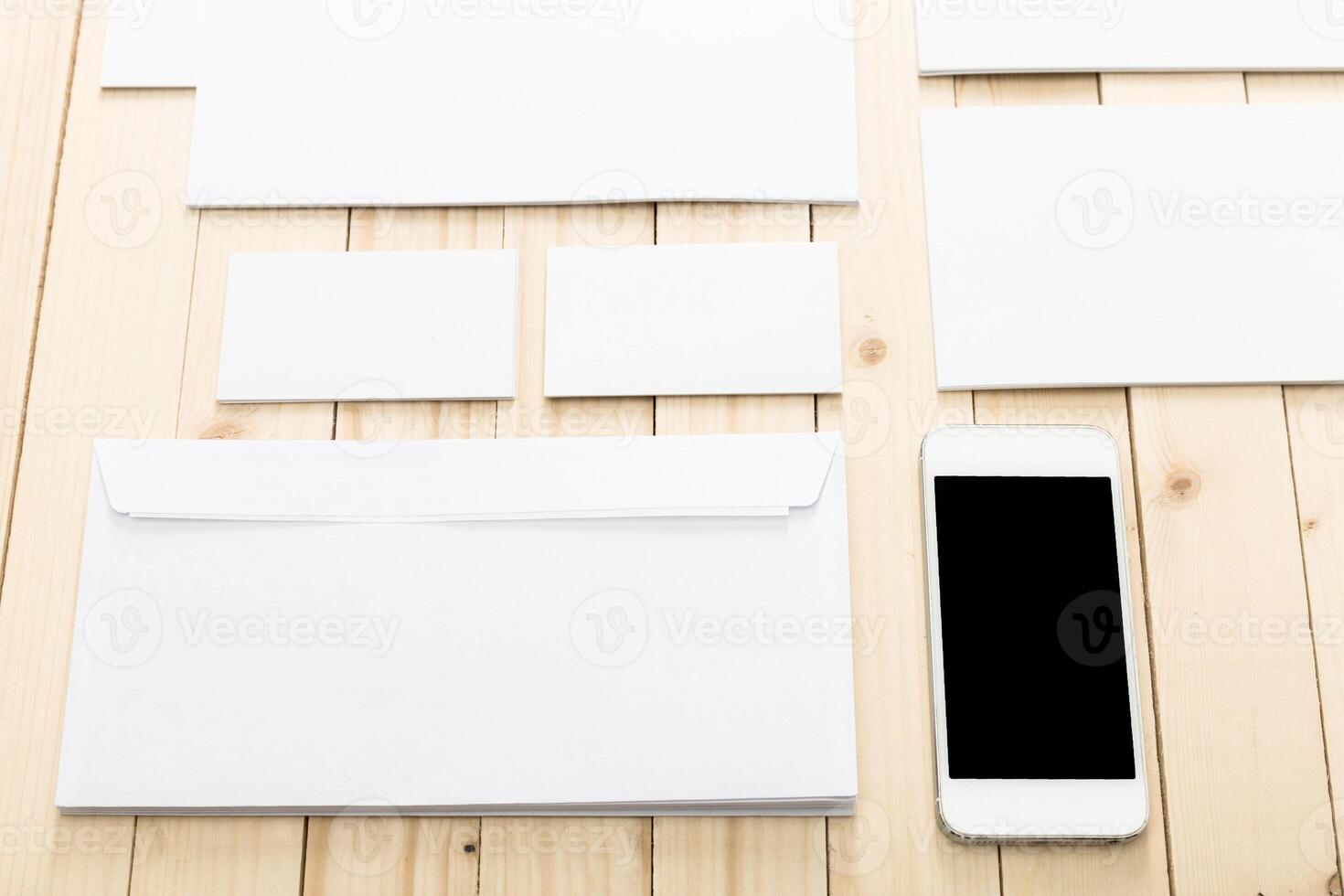 Blank stationery and smartphone arranged on a wooden table for business or personal branding projects photo