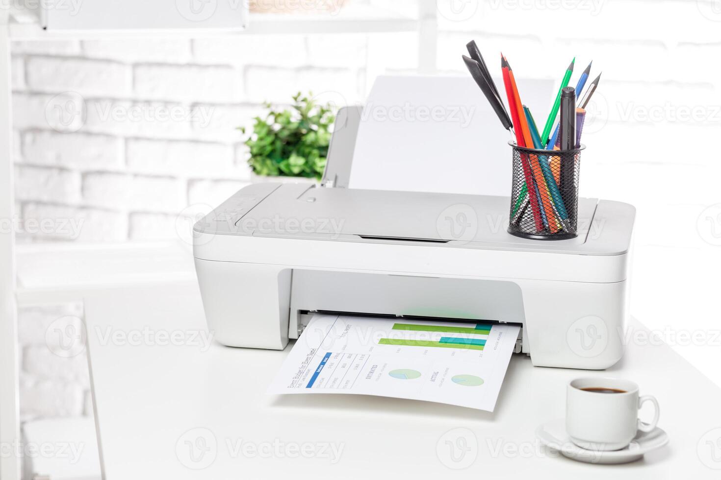 Printer on a desk prints documents while colorful pens stand in a holder near a cup of coffee in a bright workspace photo