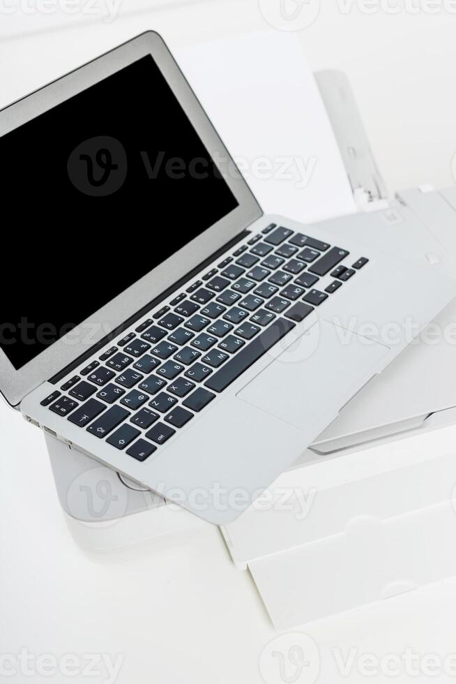 Laptop on a printer in a modern office setting with minimalistic design during daytime photo
