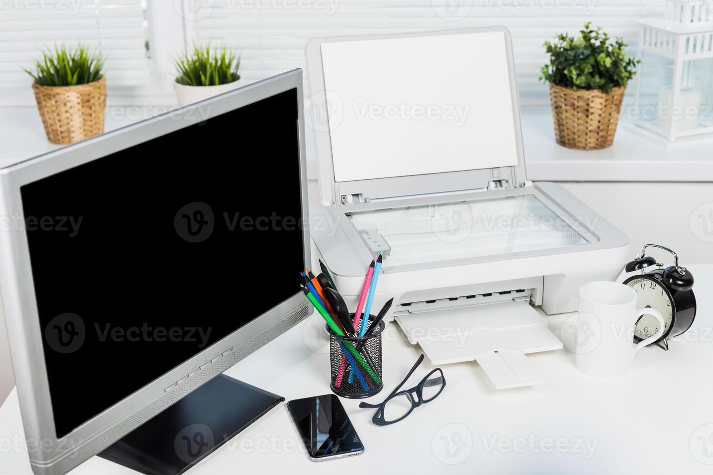 Office workspace with a computer monitor, printer, and stationery set during a morning routine photo