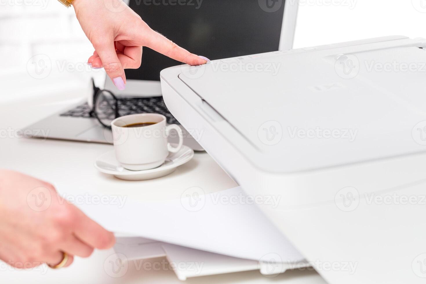 Person scanning documents at a desk with a computer and coffee cup in a bright workspace photo