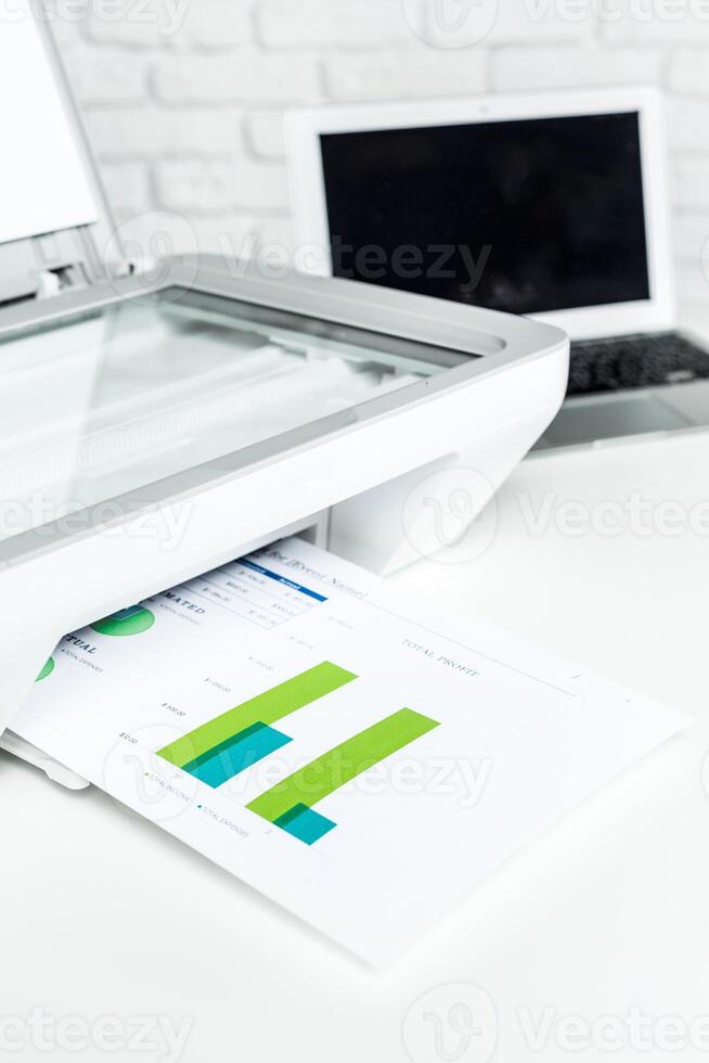 Scanning documents and graphs in a bright office environment with a laptop nearby photo