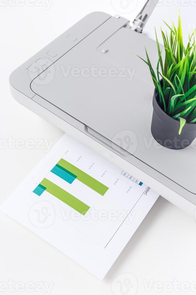 Printer in a modern office with a potted plant and printed graph displayed on the table photo