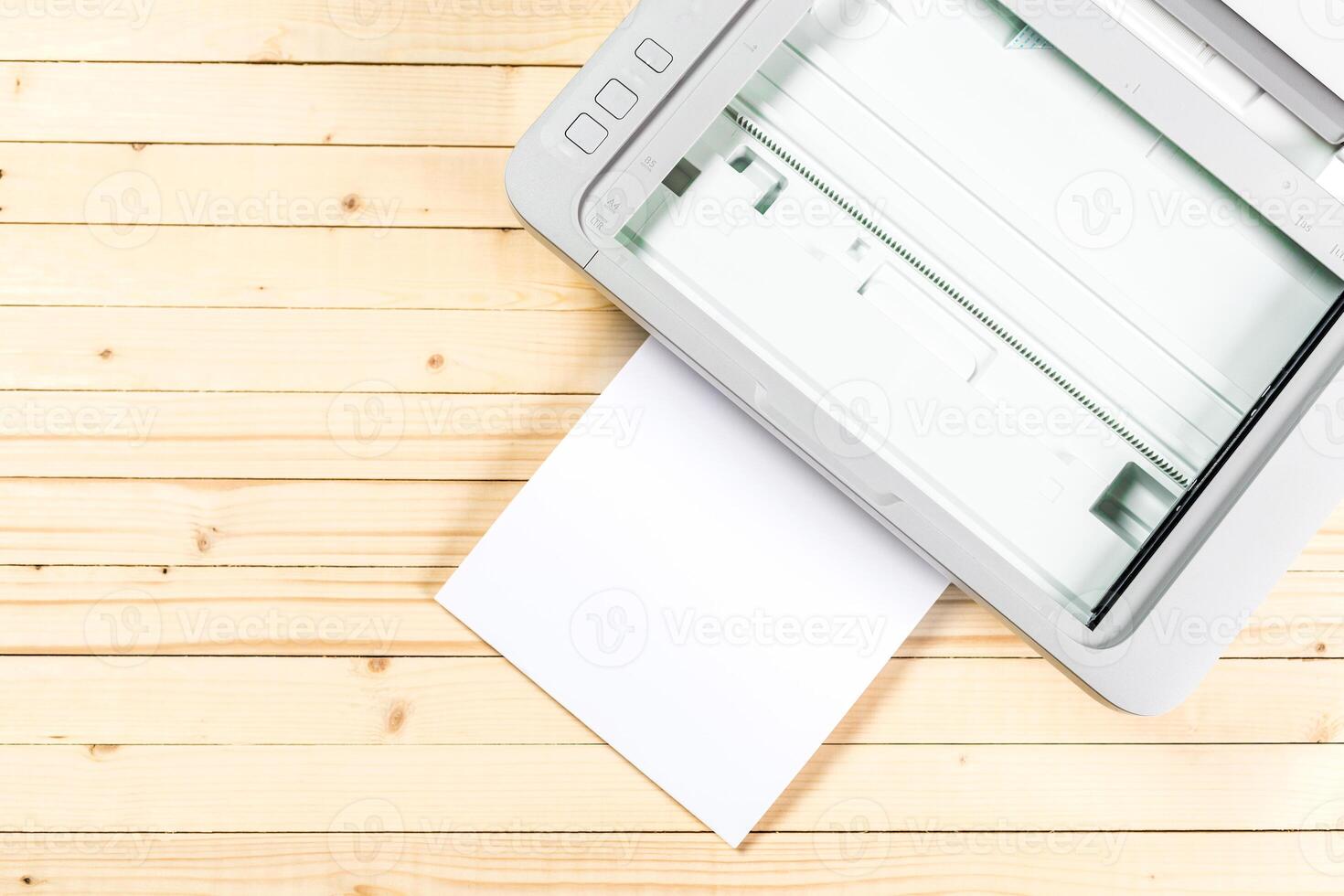 Scanner ready to process white paper against a wooden tabletop in a well-lit workspace photo