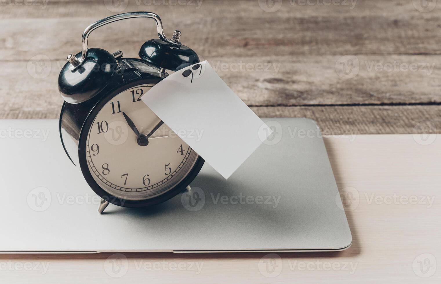 Vintage alarm clock on a modern laptop, showcasing the contrast of time in a digital age setting photo