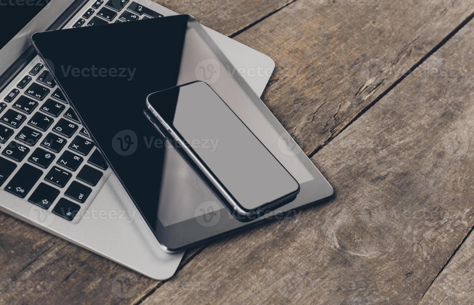Workspace setup with laptop, tablet, and smartphone on wooden table photo