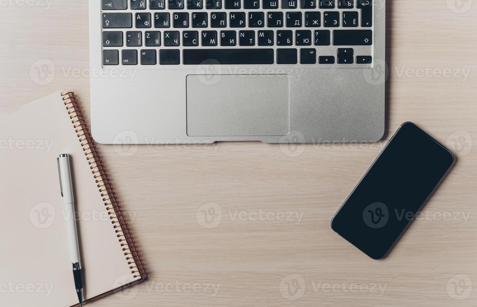 Workspace setup with a laptop, notebook, pen, and smartphone on a wooden table photo