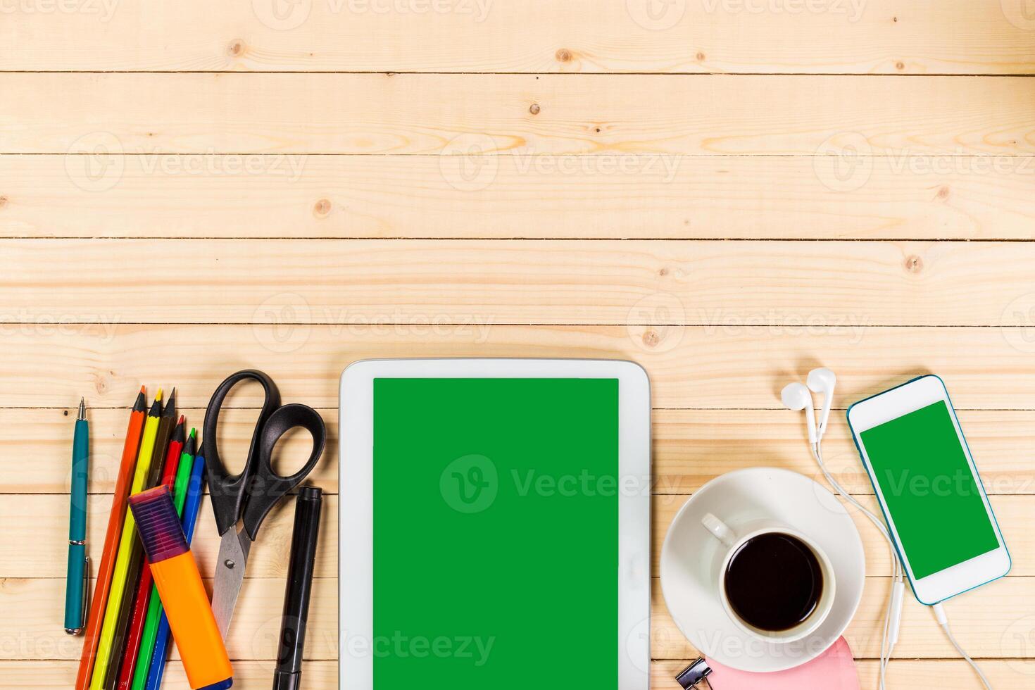 Workspace setup with tablet, smartphone, stationery, and coffee on wooden table photo
