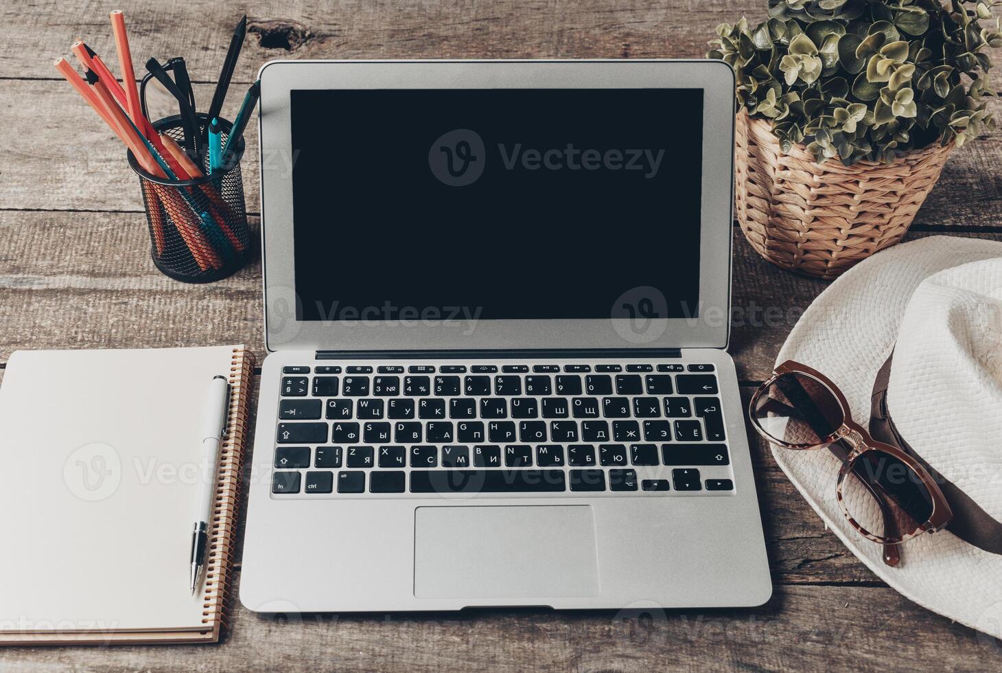 Workspace setup with laptop, notebook, and accessories on wooden table for creative planning and productivity photo