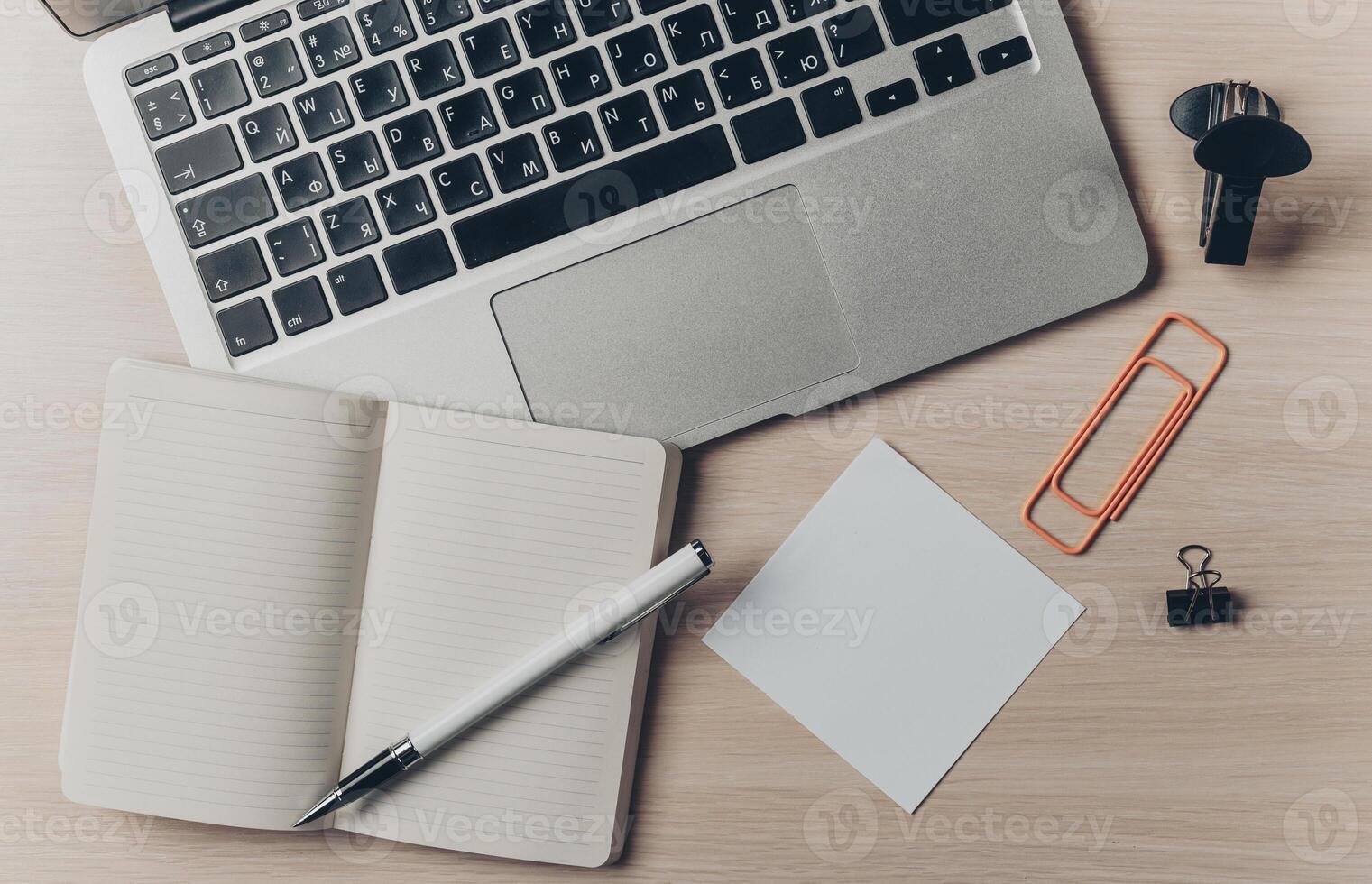 Workspace arrangement with laptop, notebook, and stationery on wooden table photo