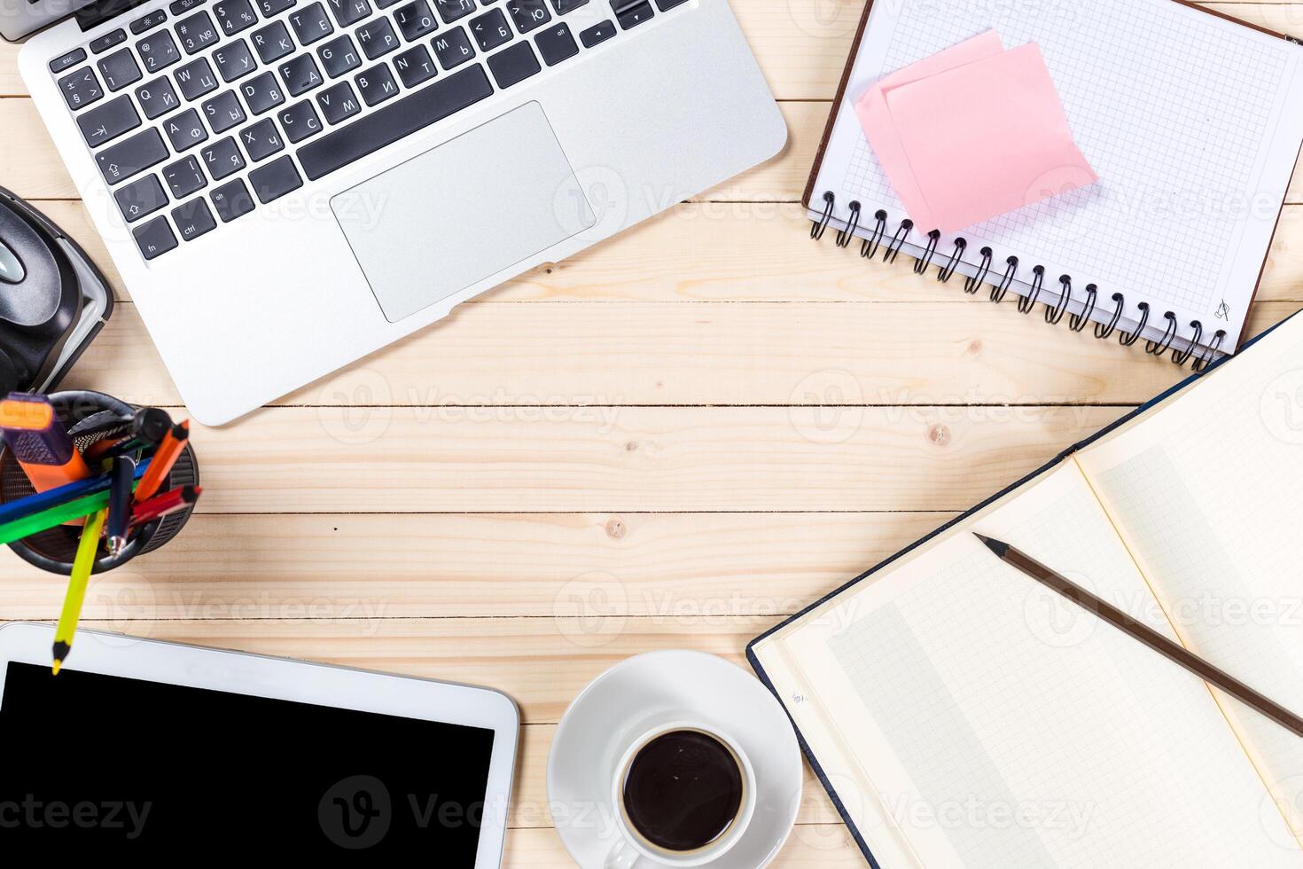 Workspace setup featuring a laptop, notebook, coffee cup, and stationery on a wooden table photo