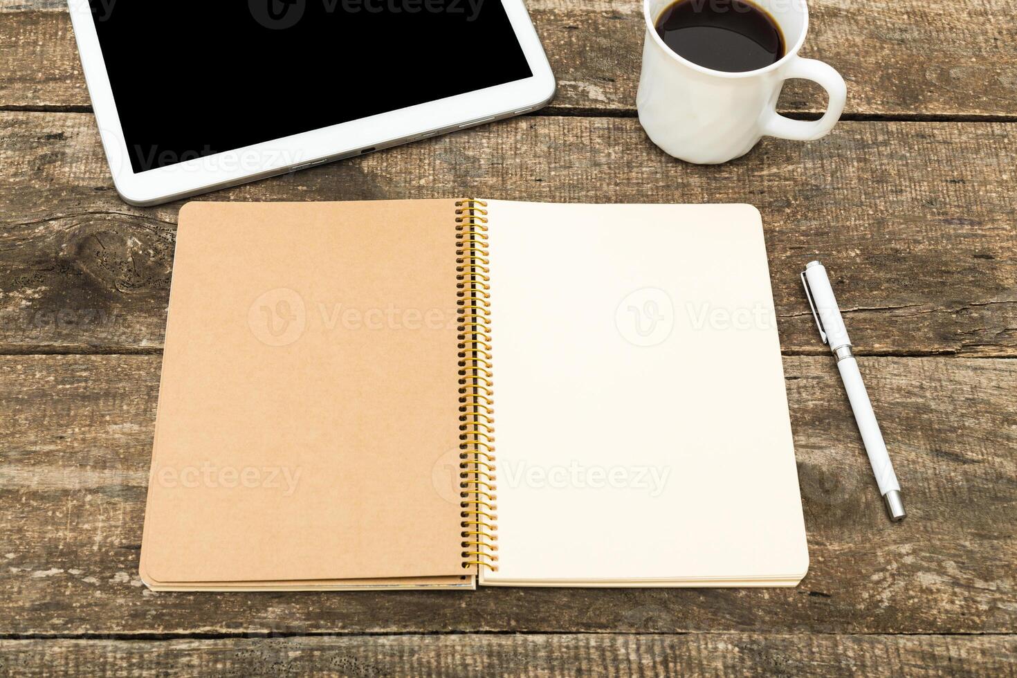 Blank notebook and tablet on a wooden table with a cup of coffee ready for writing or brainstorming ideas in a cozy workspace photo