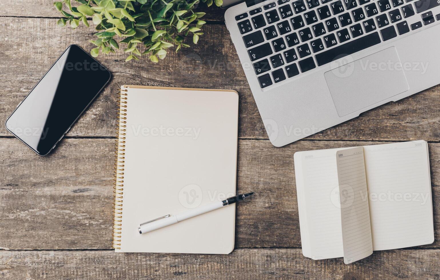 Workspace with a laptop, smartphone, and notepads on a wooden table ready for productive tasks photo