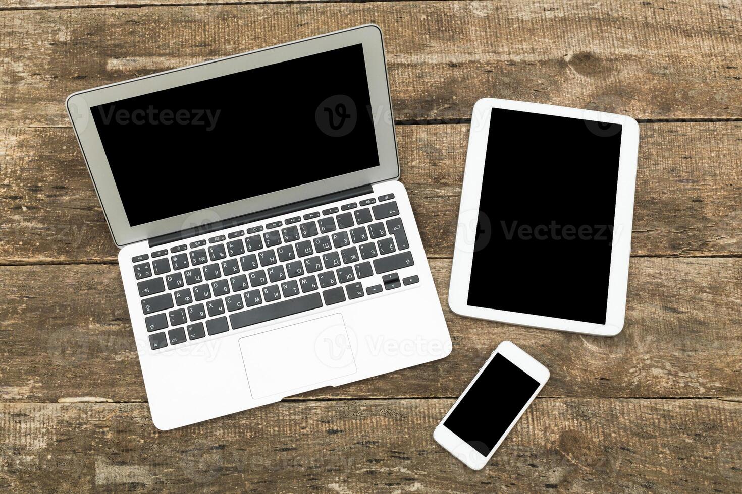 Modern workspace setup featuring laptop, tablet, and smartphone on wooden table photo