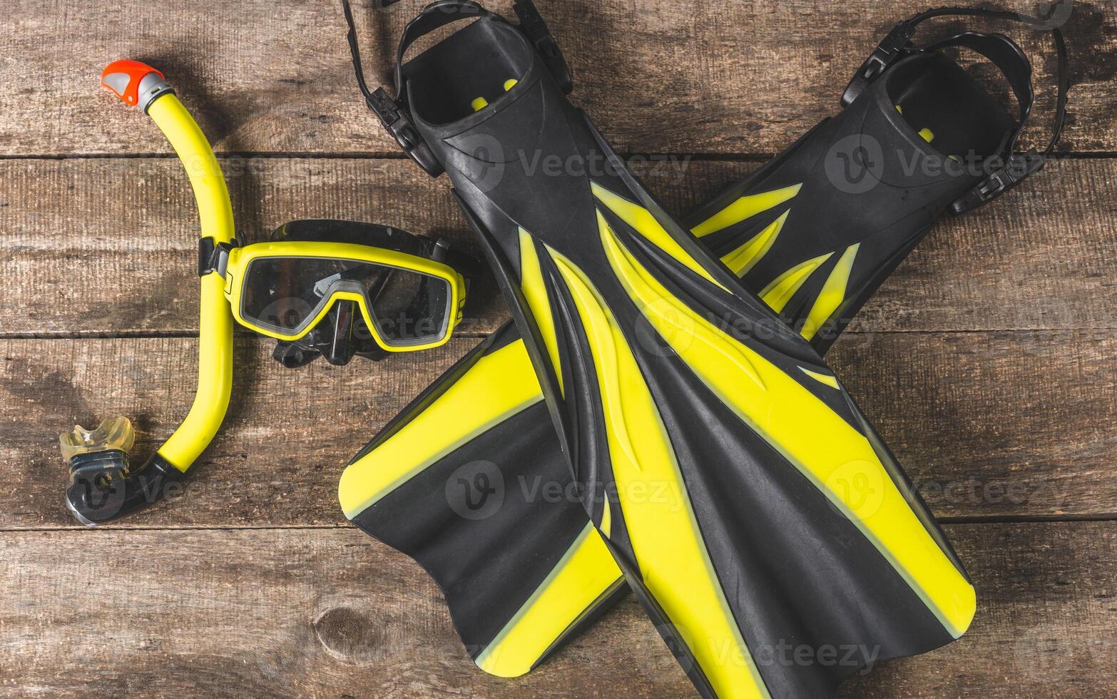Snorkeling gear arranged on a wooden surface showcases vibrant fins and mask, perfect for underwater adventures photo