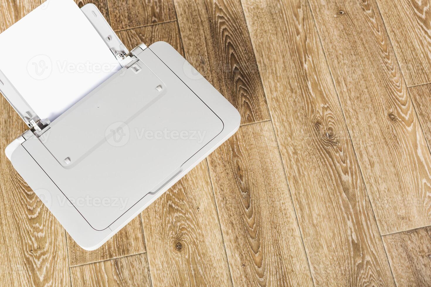 Printer on wooden floor with open tray ready for documents at home office workspace during daytime photo