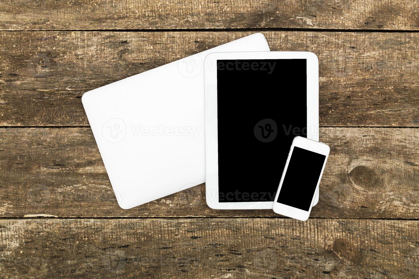 Modern technology devices arranged on wooden surface showcasing a laptop, tablet, and smartphone photo