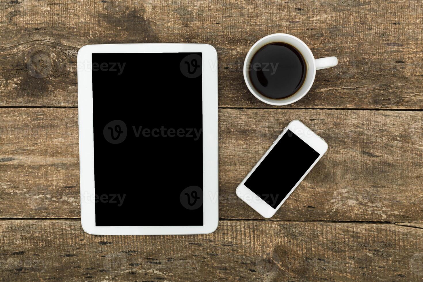 Digital devices and a cup of coffee on a rustic wooden table in a calm workspace setting photo