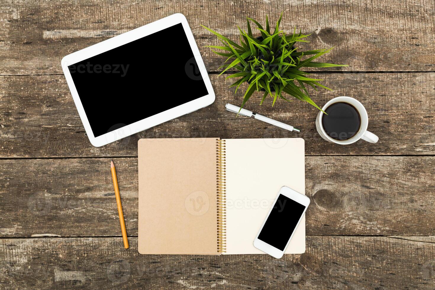 Workspace setup with digital devices, stationery, and a coffee cup on a rustic wooden table photo