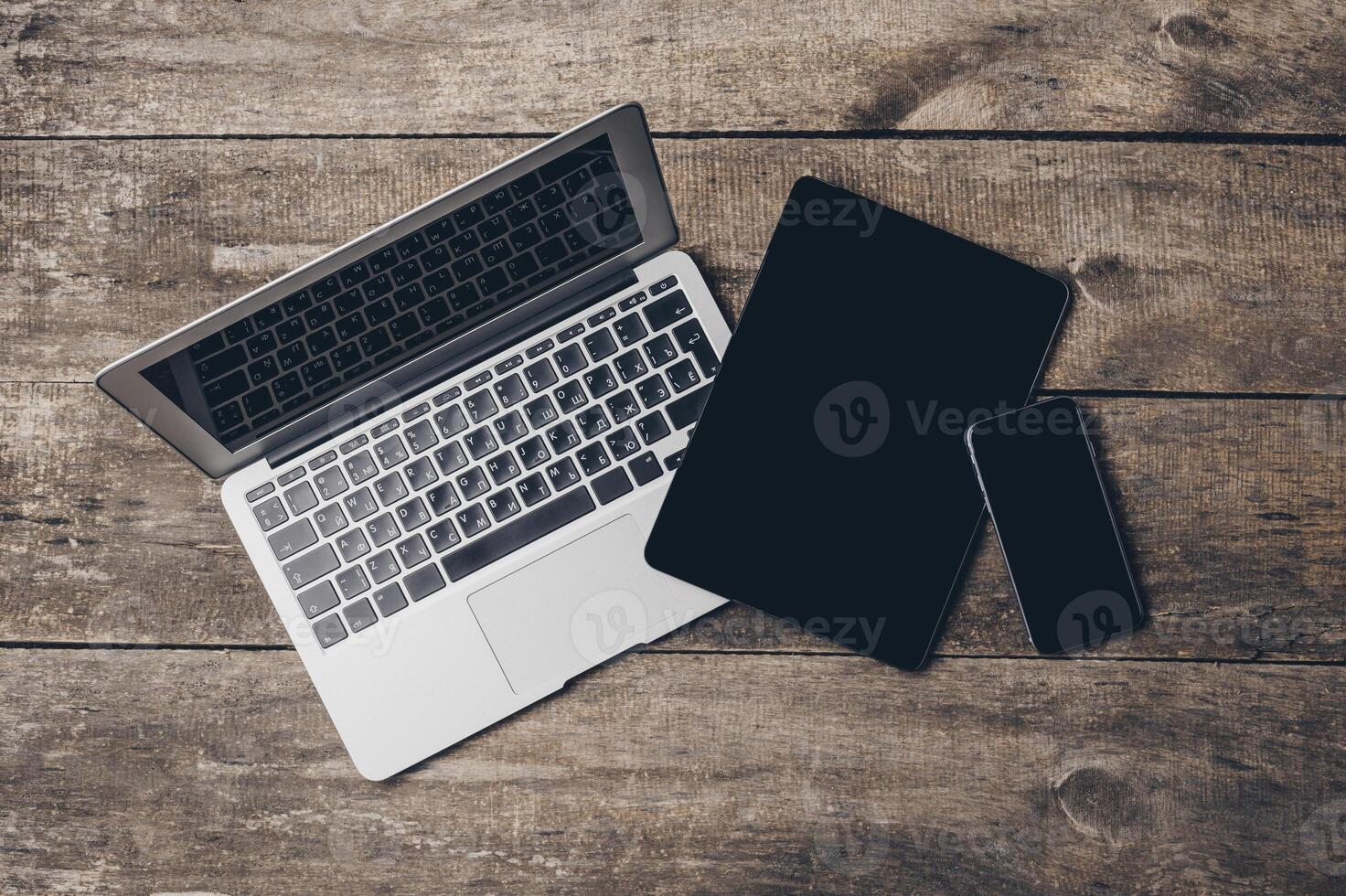 Multiple digital devices arranged on a wooden surface with a natural aesthetic during daylight hours photo