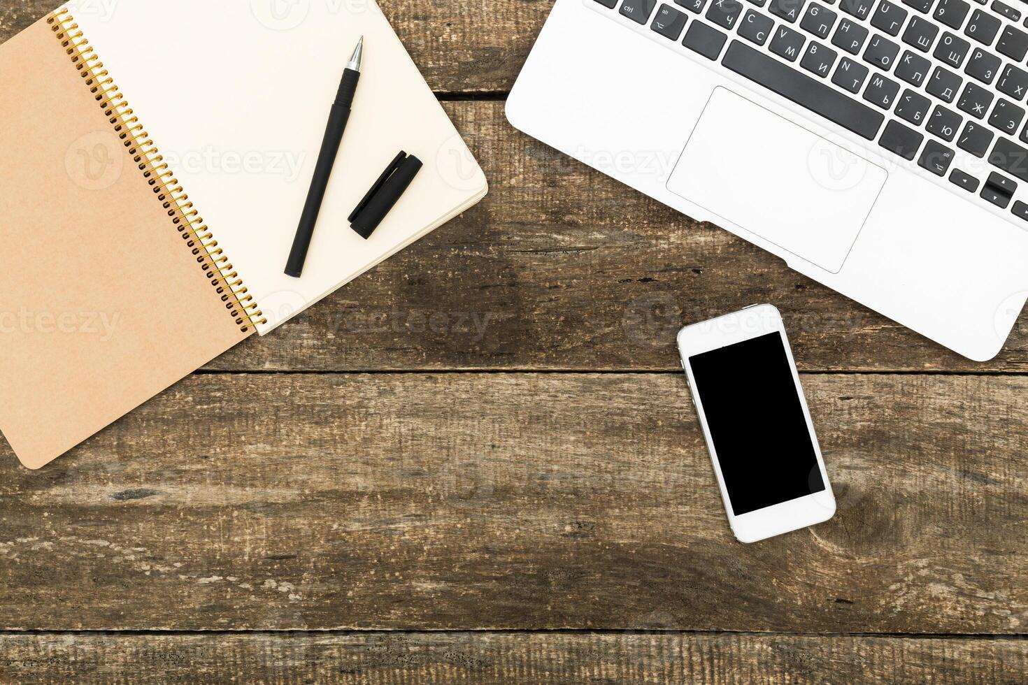 Notepad, pen, smartphone, and laptop arranged on wooden table for creative brainstorming session photo