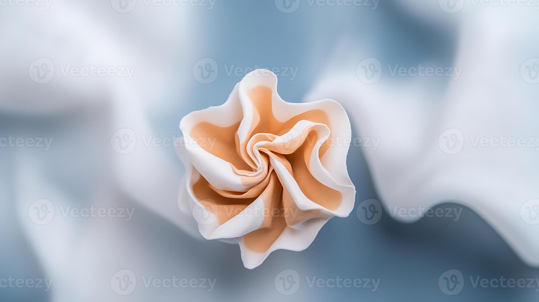 A delicate, handcrafted flower made of soft fabric resting on a smooth, light blue backdrop photo