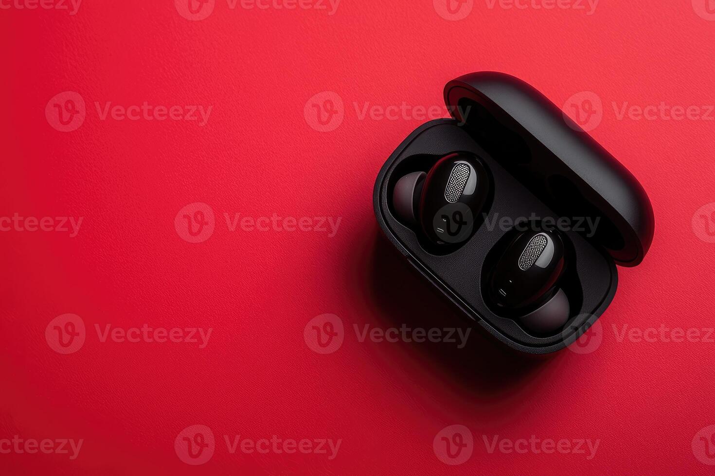 Sleek black wireless earbuds on vibrant red background. photo