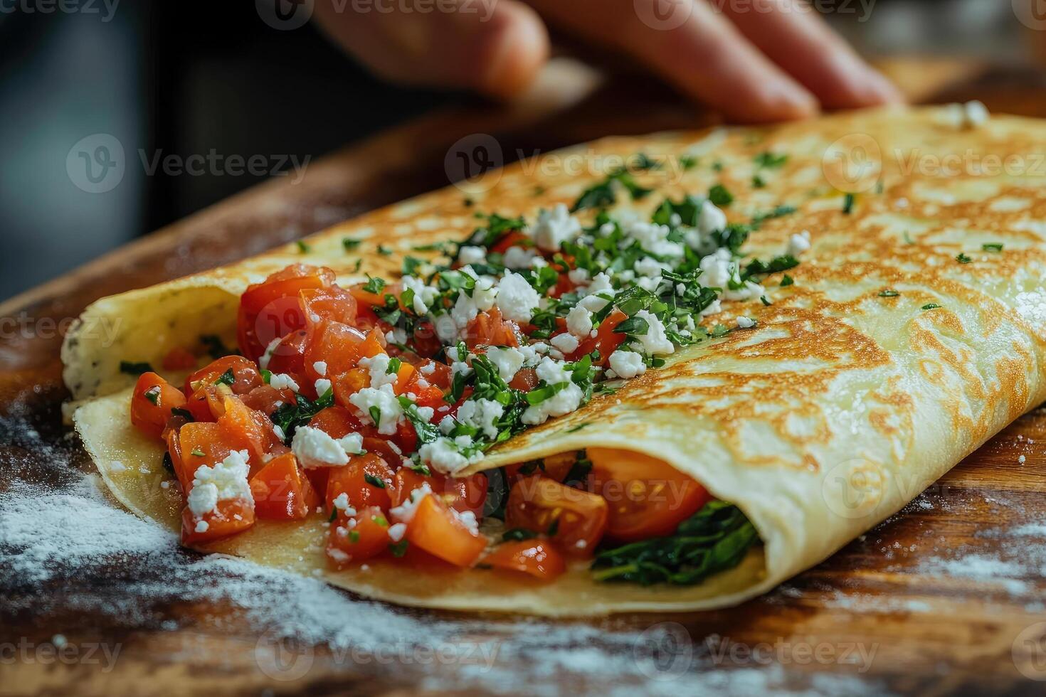 Chef preparing savory crepe with tomatoes, spinach, and feta cheese photo