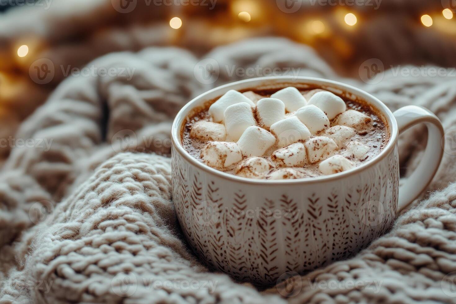 Hot chocolate with marshmallows on cozy knitted blanket near glowing christmas lights photo
