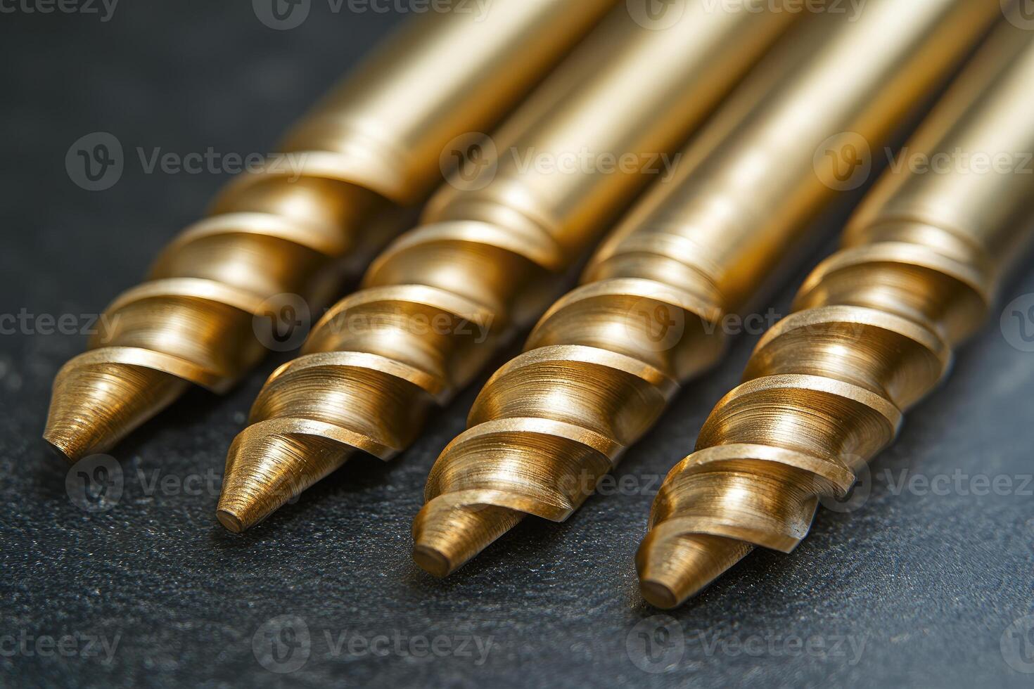 Golden drill bits resting on dark surface showing sharp threads photo