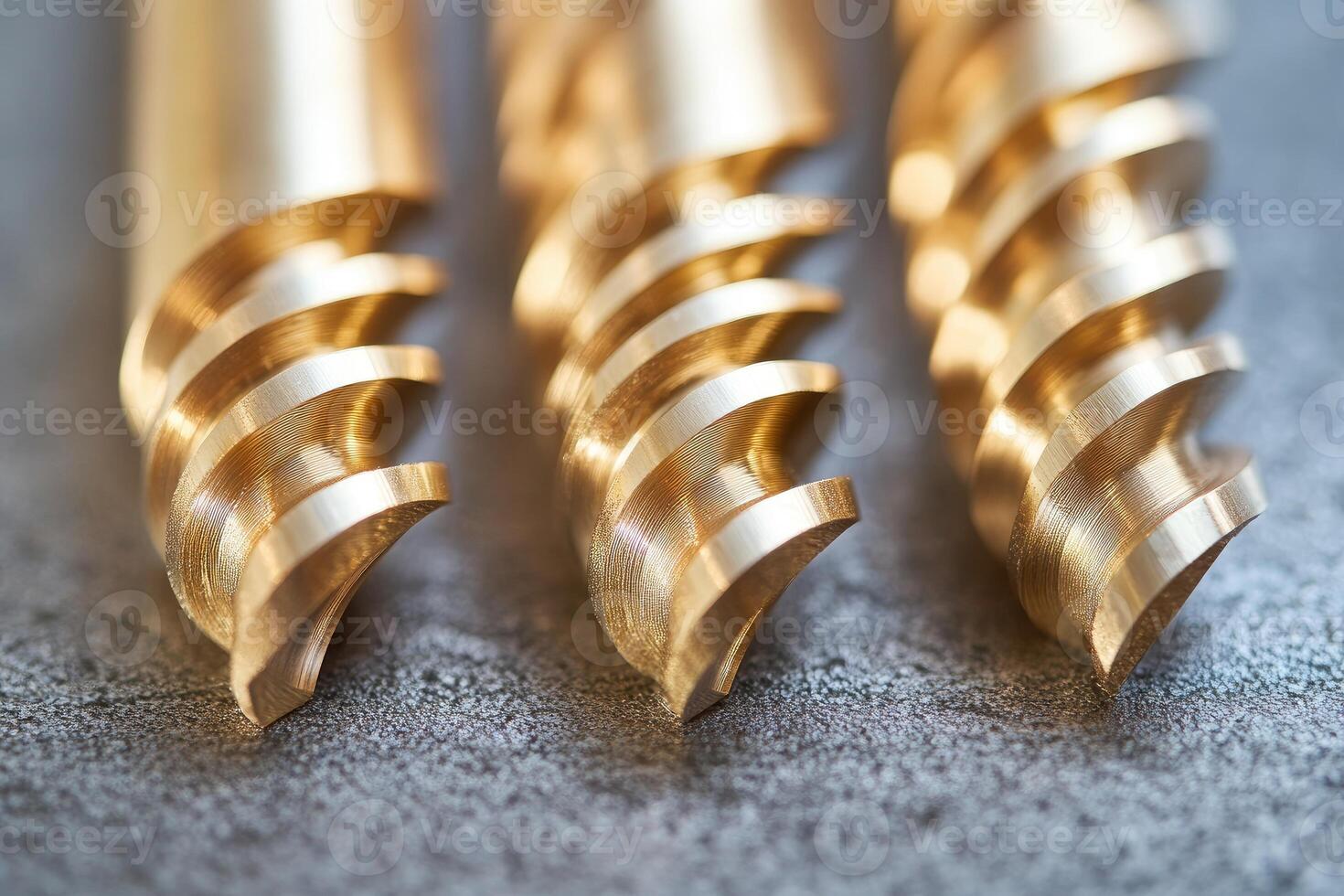 Golden drill bits resting on dark surface showing sharp threads. photo