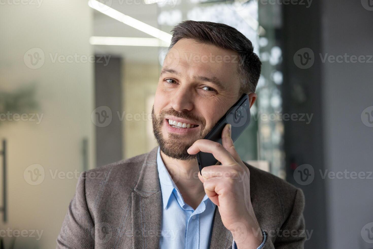 Smiling business professional in a modern office environment having a phone conversation on a smartphone. photo