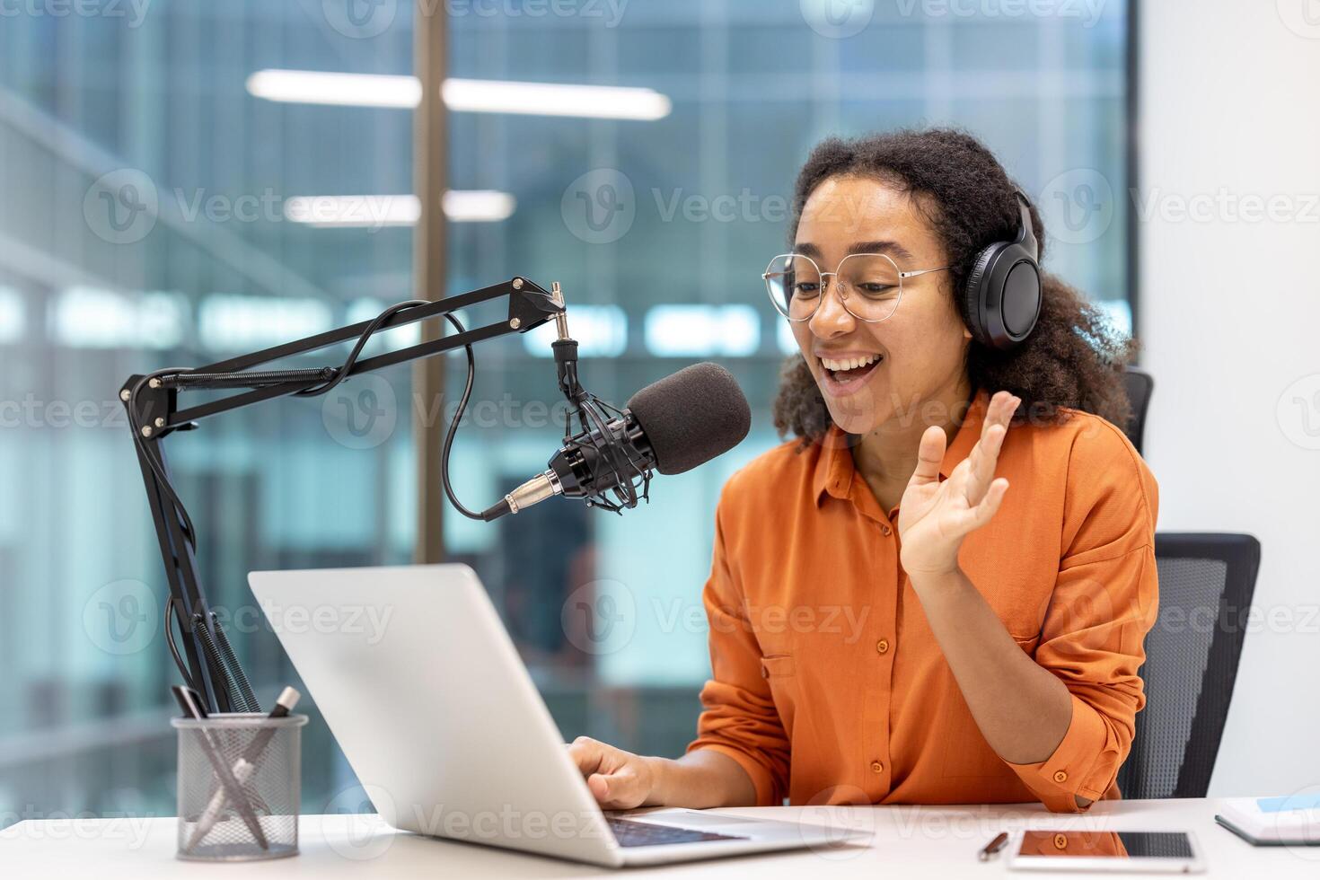Woman blogger recording podcast and online training course. Influencer using professional microphone and laptop for streaming, sitting by the window inside modern studio. photo