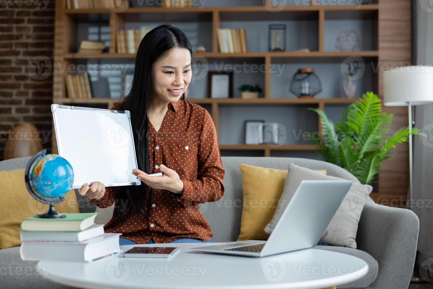 Asian woman conducting an online lesson with laptop and whiteboard. Engaging interaction through digital medium, integrating global and educational concepts from home. photo
