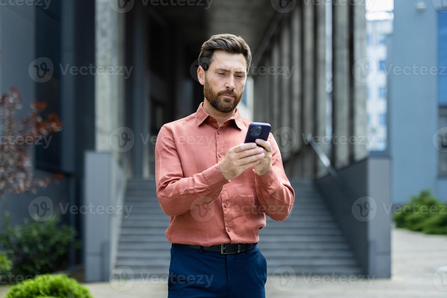 Serious thoughtful man thinks while reading emails, businessman walks with smartphone in hands uses messaging app. photo