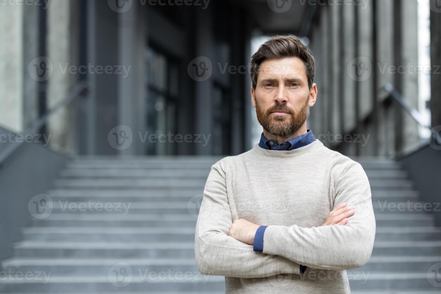 Confident businessman with beard stands with arms crossed, exuding strength and determination. Professional attire emphasizes leadership qualities. photo