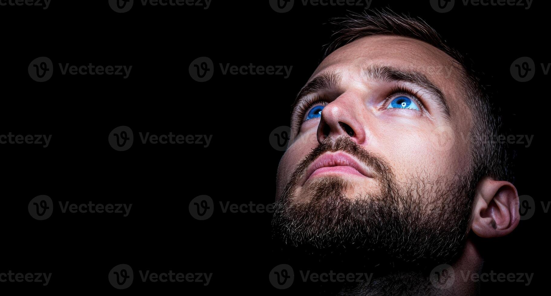Man looking up with blue eyes in the dark photo