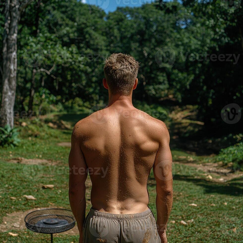 Fit man standing in nature with a muscular back photo