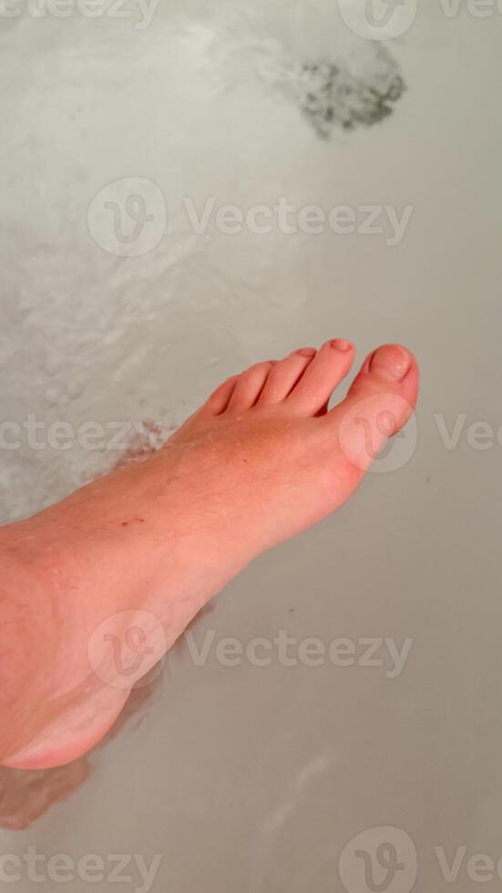 A close up of a Caucasian persons foot submerged in water, symbolizing relaxation and personal care photo