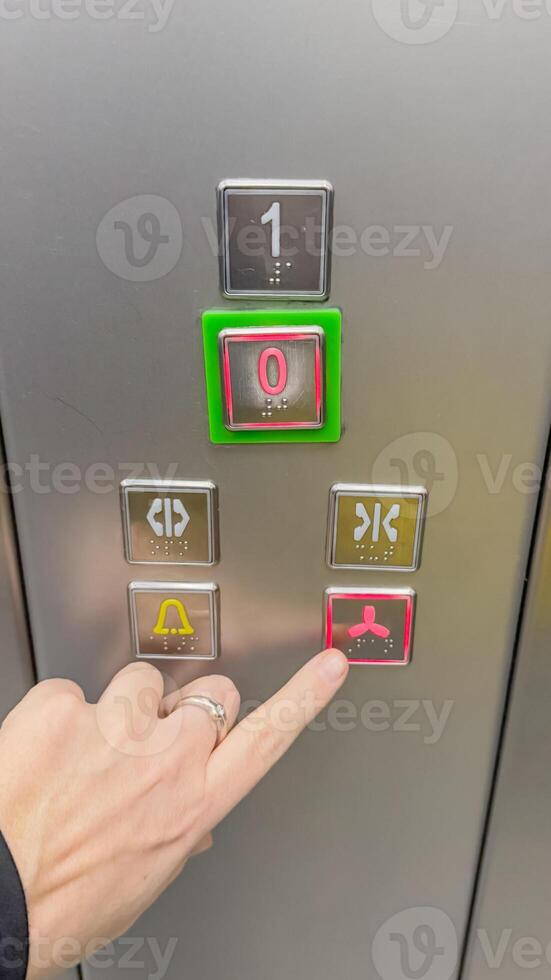 A person with a gold wedding ring pushes the basement button on an elevator panel, symbolizing accessibility and convenience photo
