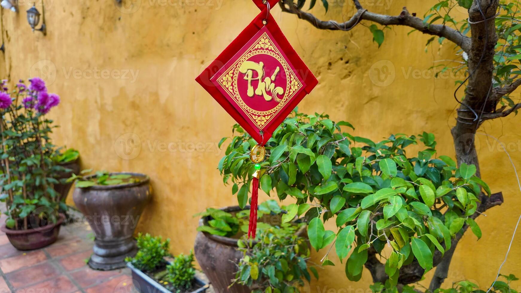 A traditional Vietnamese decorative banner hangs amidst potted plants, celebrating the Lunar New Year with vibrant cultural symbols photo