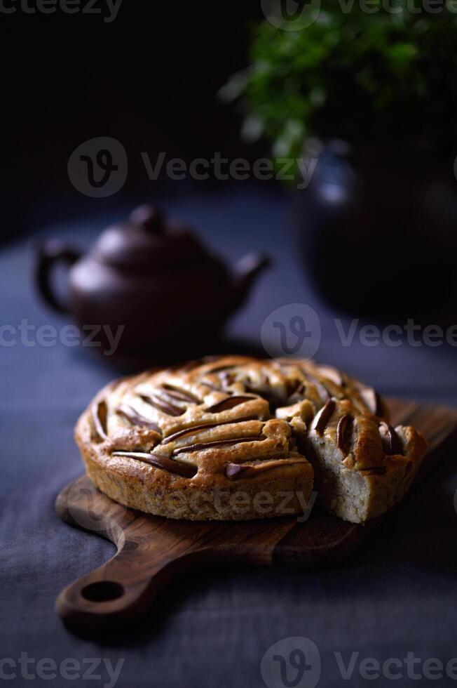 A fruit cake or a muffin or a pie with a clay pot and herbs. Flat lay. photo