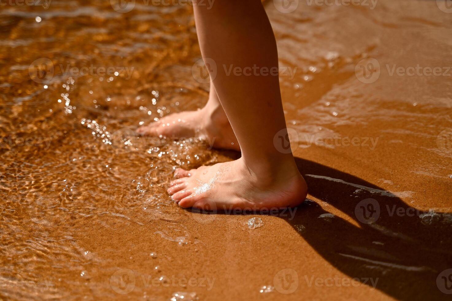 Kid's feet in the sand on the beach photo