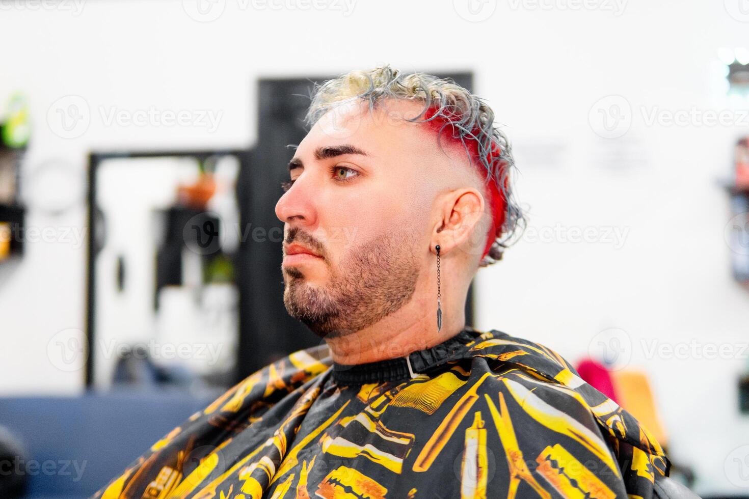 Hispanic man getting a haircut with red and grey highlights in a barbershop photo