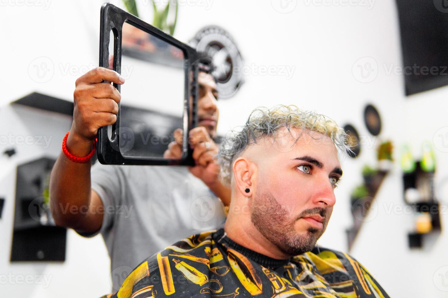 Barber showing haircut to client with hand mirror in barbershop photo
