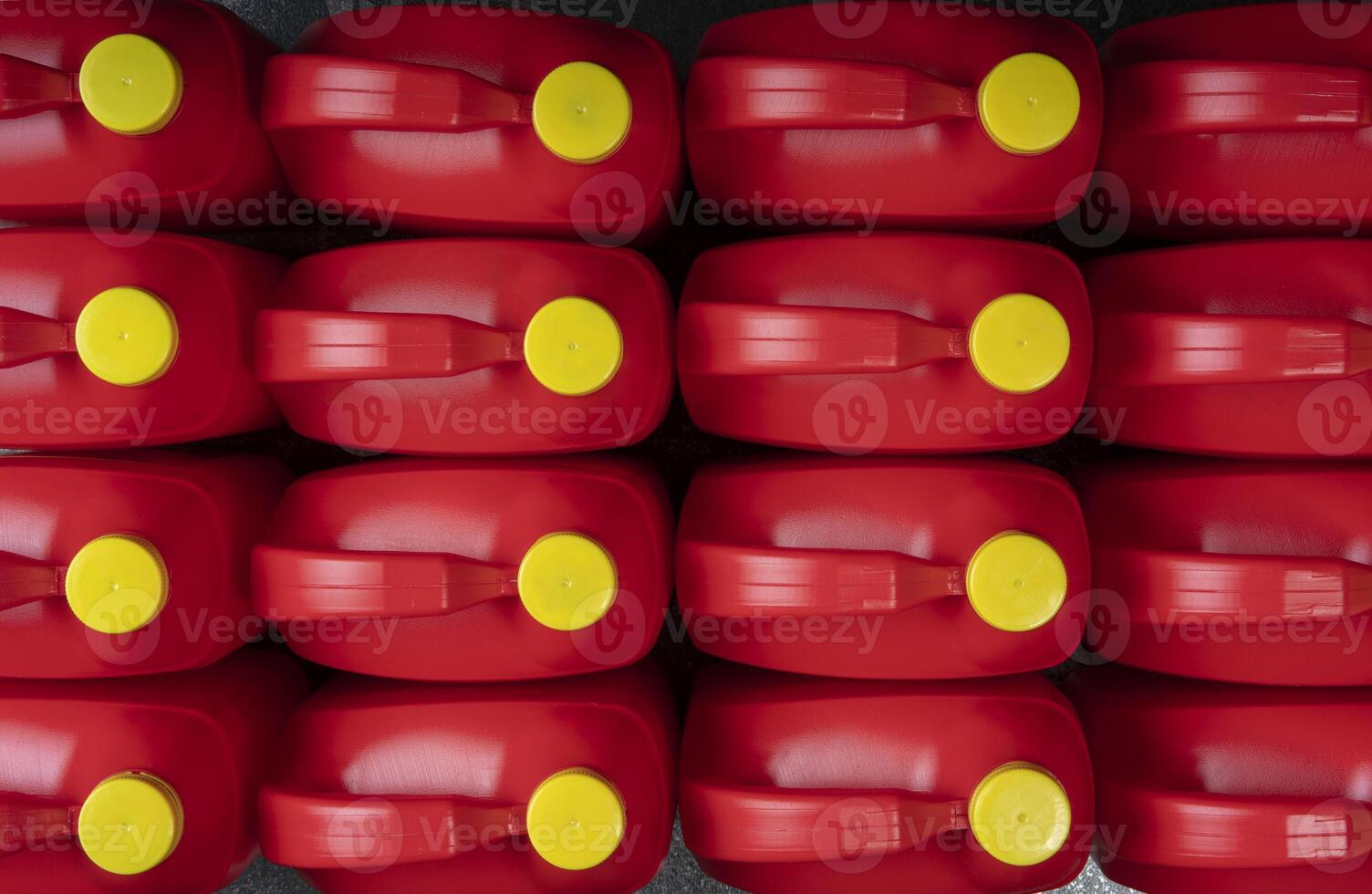 Top view of arranged red plastic motor oil bottles, containers with handle and yellow screw cap photo