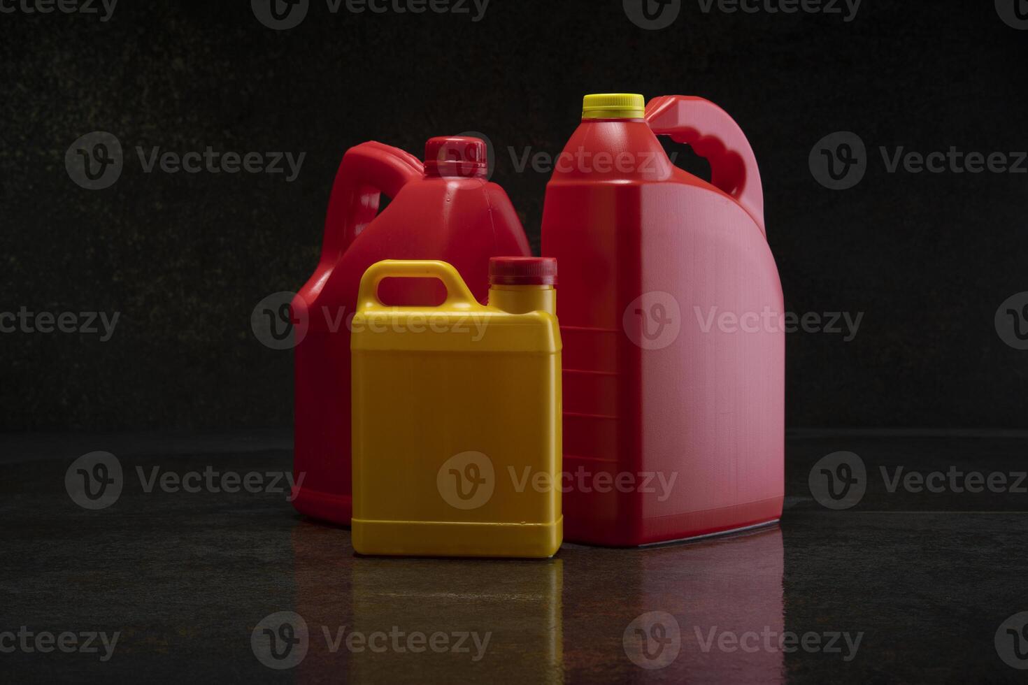 Front view of three different yellow and red plastic motor oil bottles, container with handle and screw cap without label photo