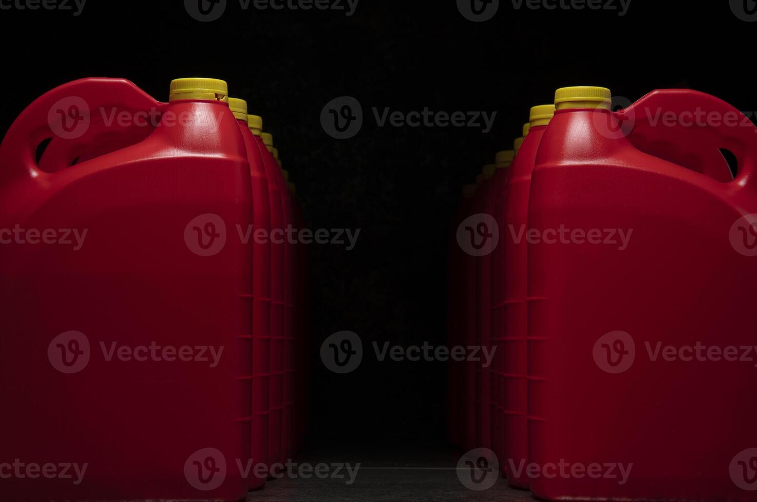 Front view of two columns of red plastic motor oil bottles forming a tunnel, containers with handle and yellow screw cap without label photo