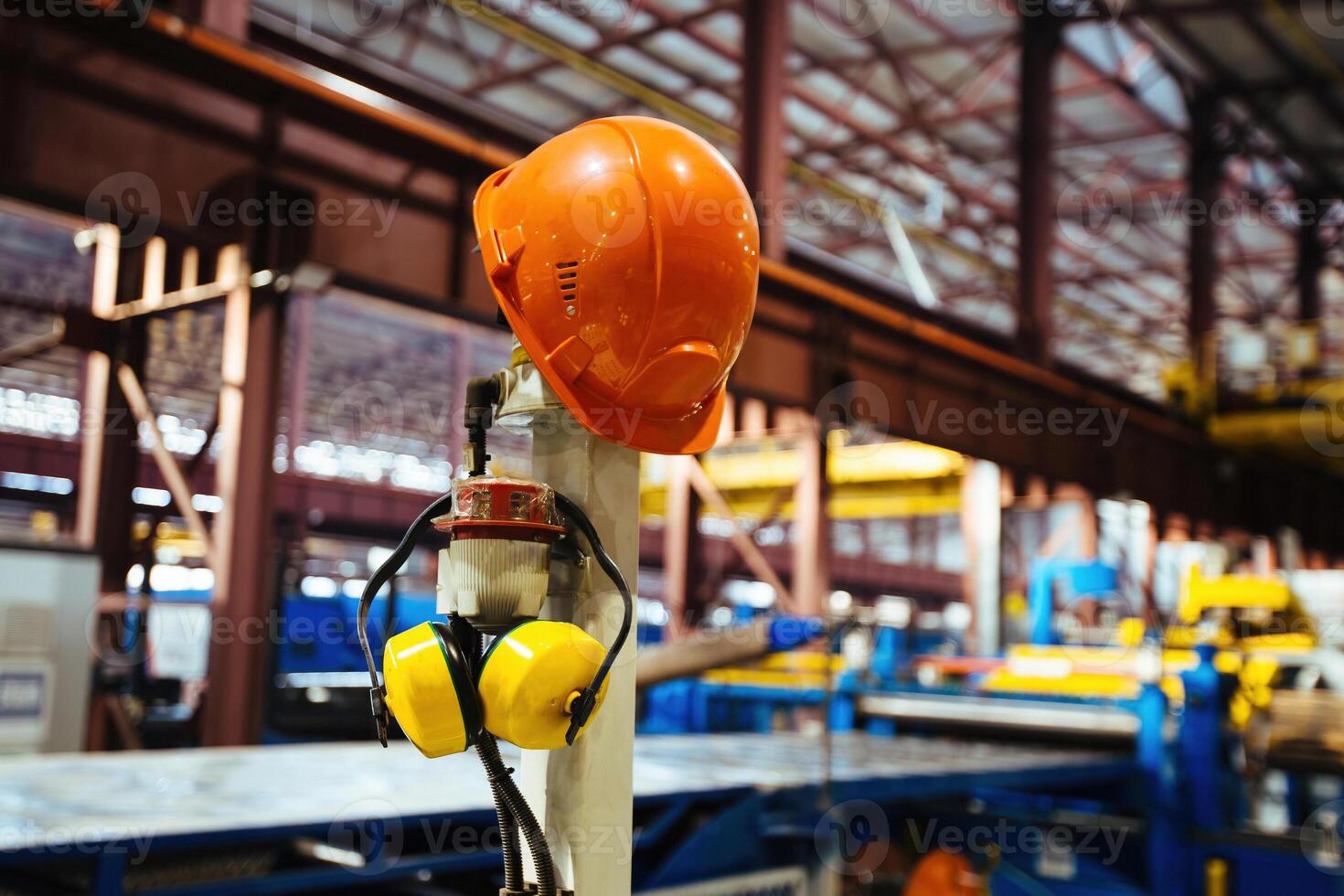Helmet and ear-phones on blurred industrial background photo