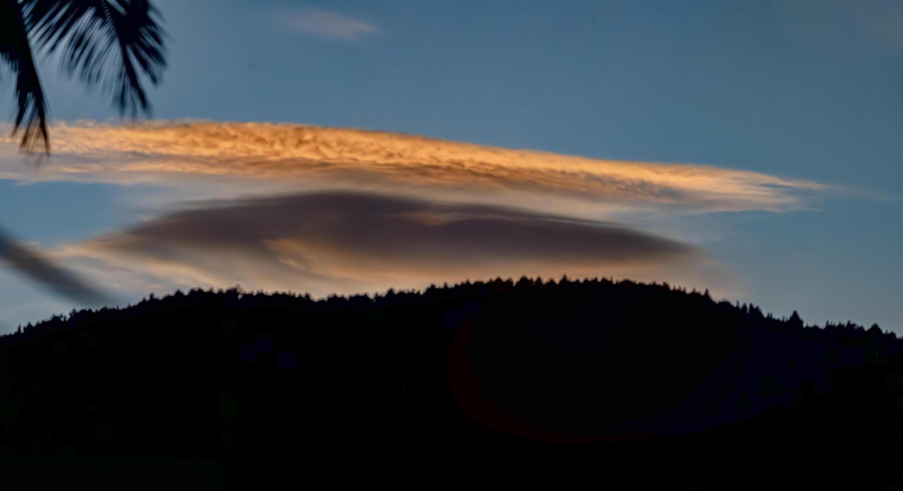 A cloud is seen in the sky over a mountain photo